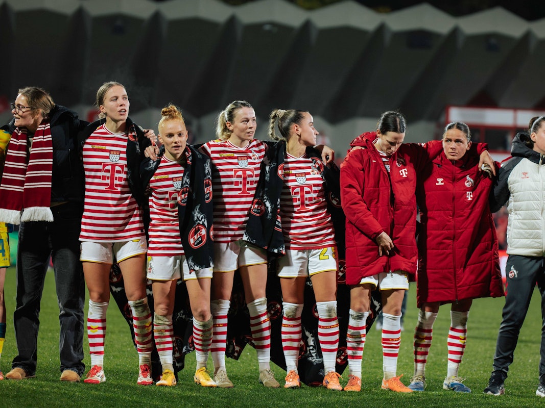Die Frauen des 1. FC Köln stehen nach einem Spiel Arm in Arm zusammen.