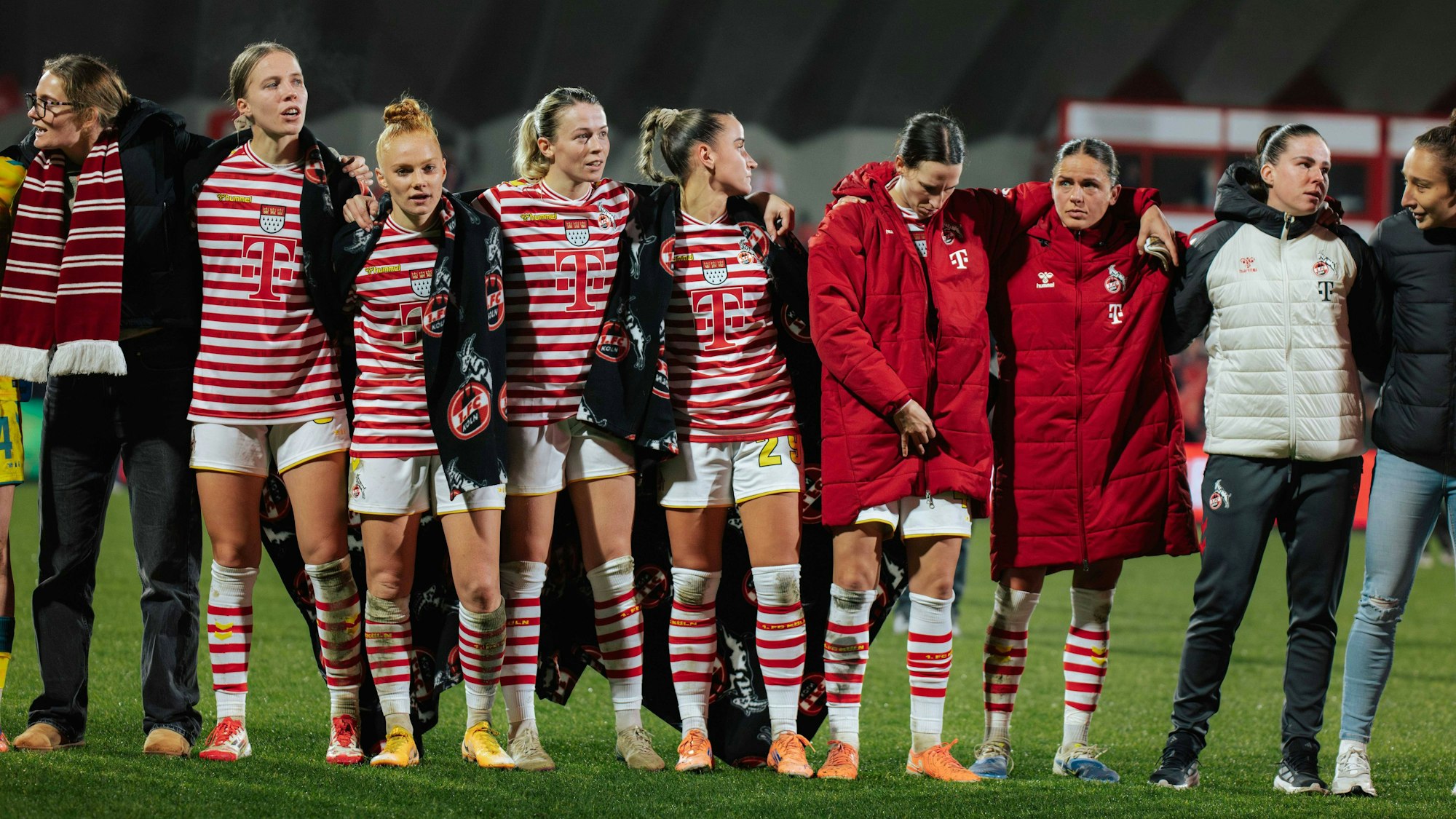 Die Frauen des 1. FC Köln stehen nach einem Spiel Arm in Arm zusammen.