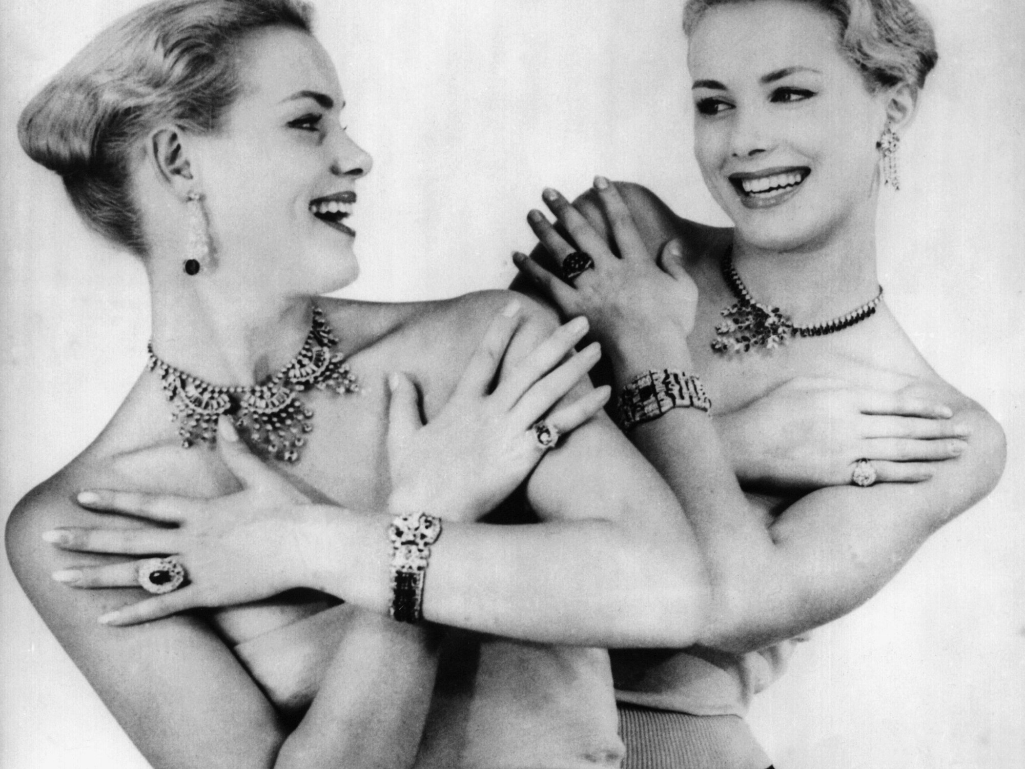 Reich behängt mit Schmuck lachen sich die deutschen Zwillinge Alice und Ellen Kessler an - aufgenommen 1956 im Pariser Lido.