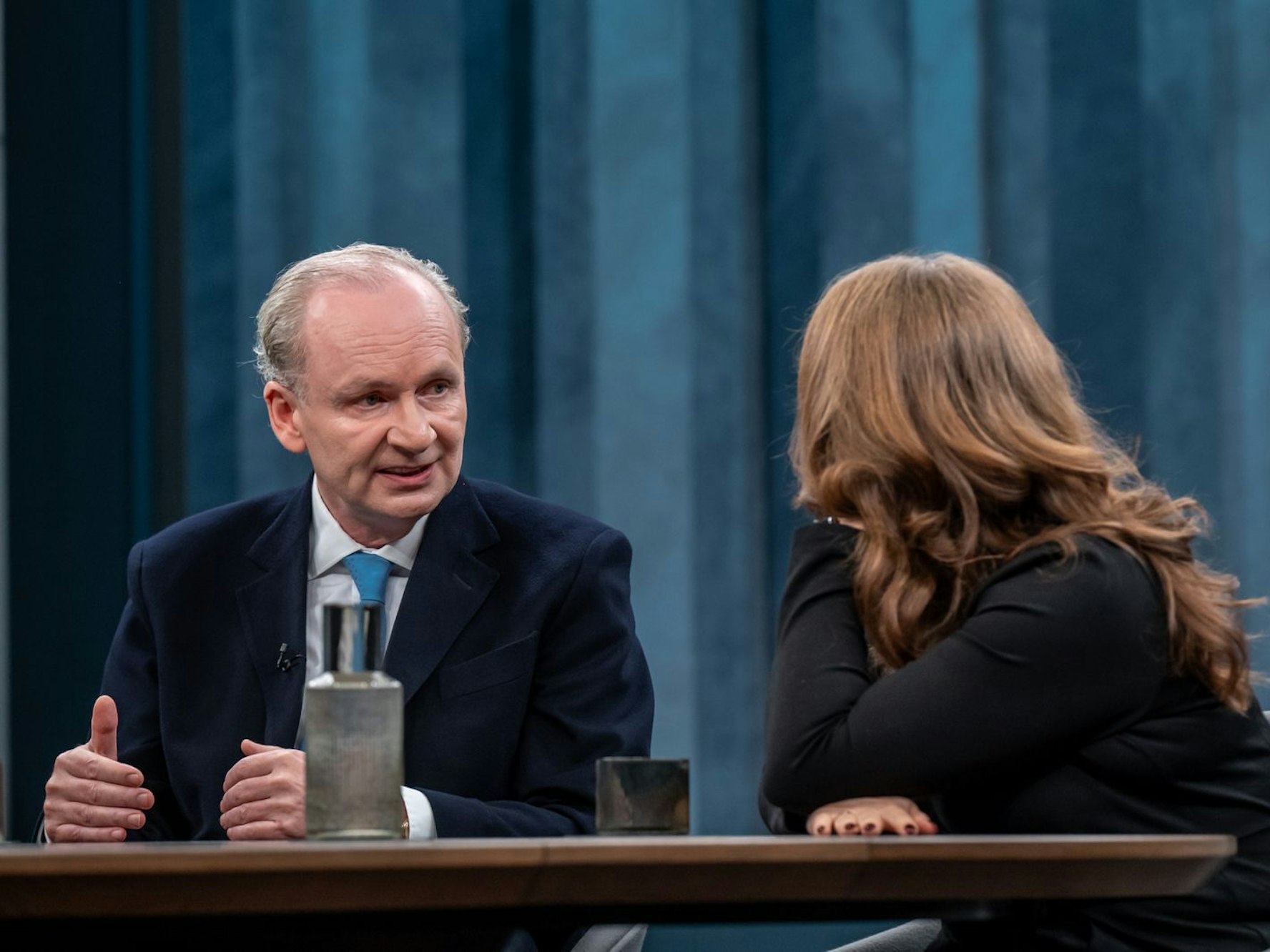 Ein Mann sitzt an einem Tisch und guckt eine Frau neben sich an.