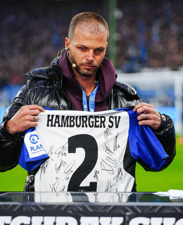 Dennis Diekmeier hält ein unterschriebenes HSV-Trikot hoch und hat dabei Tränen in den Augen.