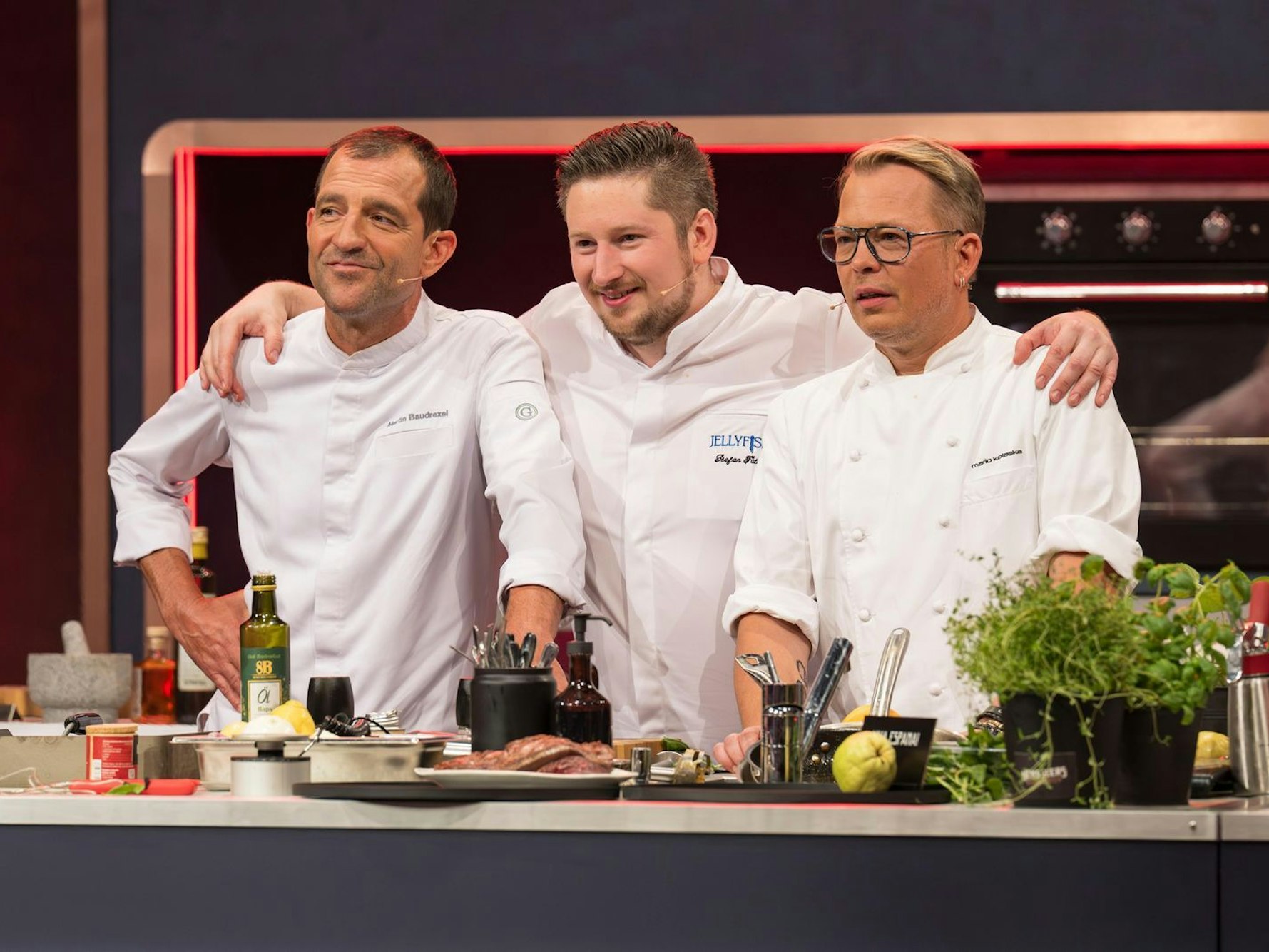 Drei Männer in Kochjacken stehen nebeneinander.