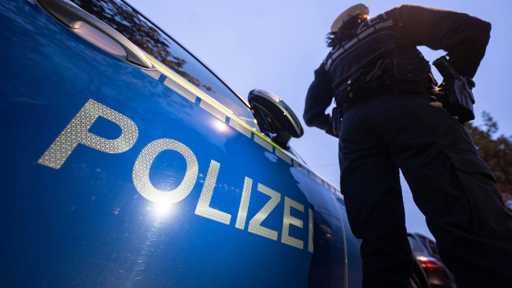 Eine Polizistin steht vor einem Polizeiauto.