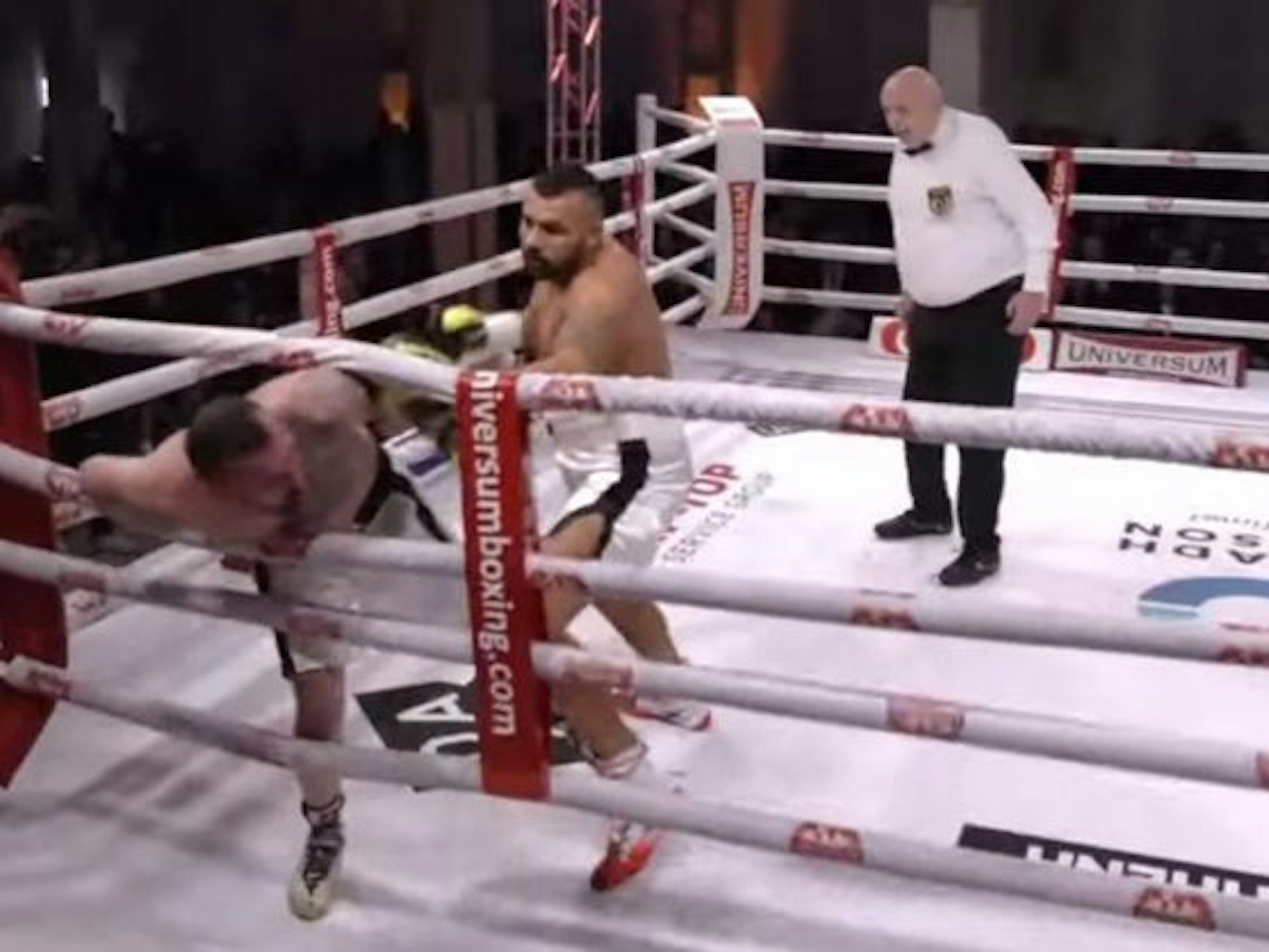 In einem Boxring schlägt ein Mann einen anderen, der bereits in den Seilen hängt.