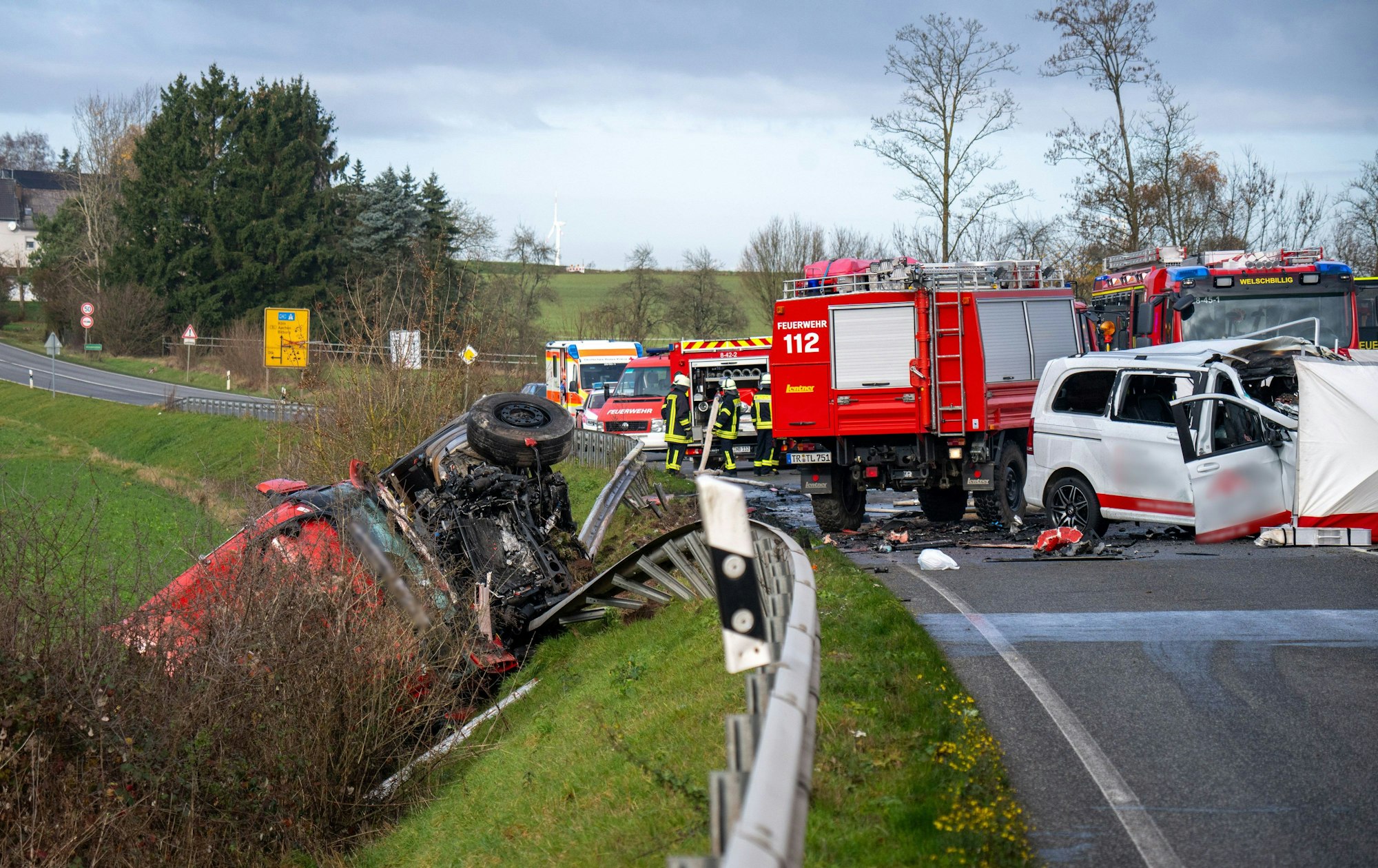 Ein Lastwagen liegt nach einem Frontalzusammenstoß mit einem Kleinbus (r) hinter der Leitplanke an einem Abhang an der Bundesstraße 51 bei Welschbillig.