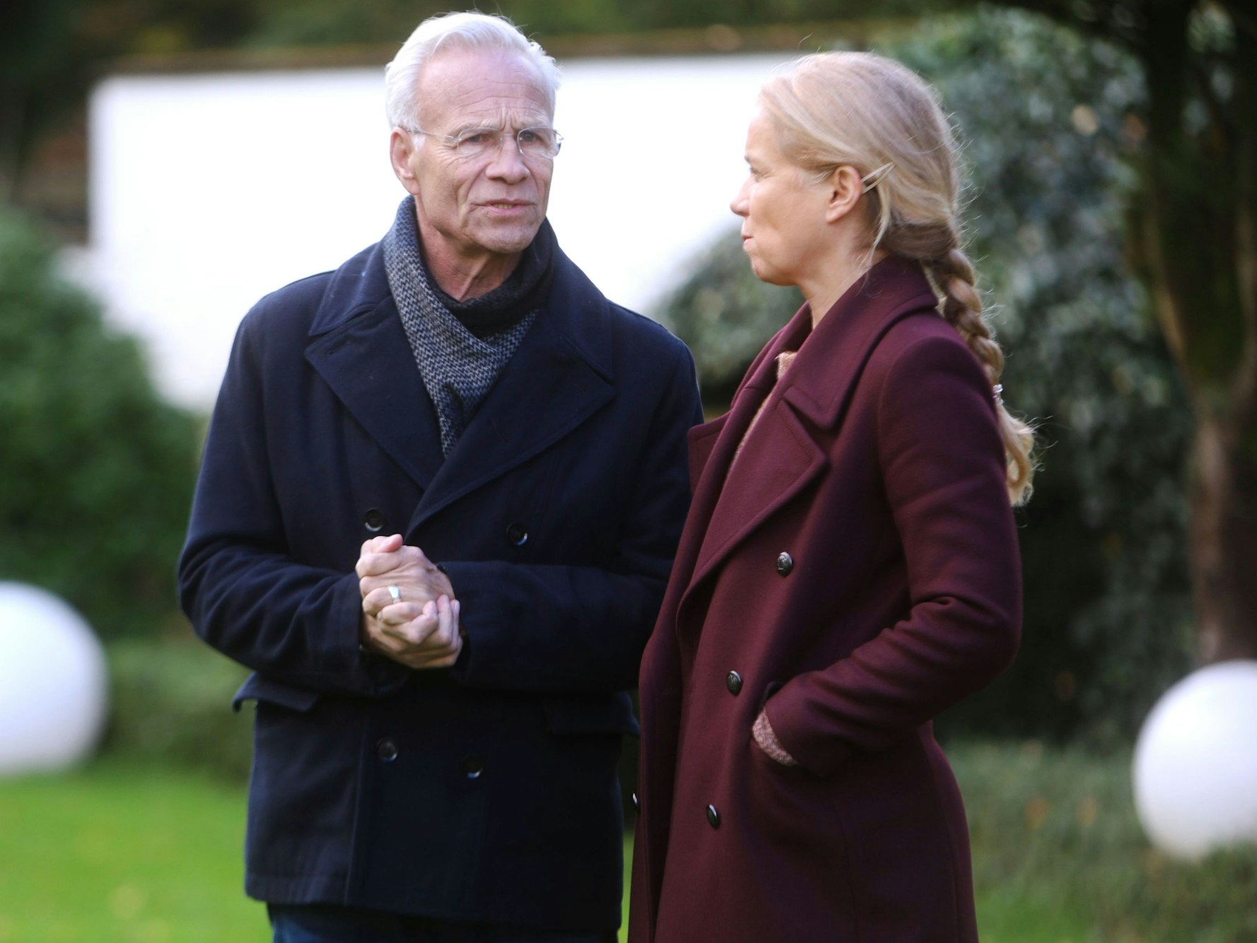 Alexandra Schalaudek und Klaus J. Behrendt stehen am Drehort im Garten einer Villa.
