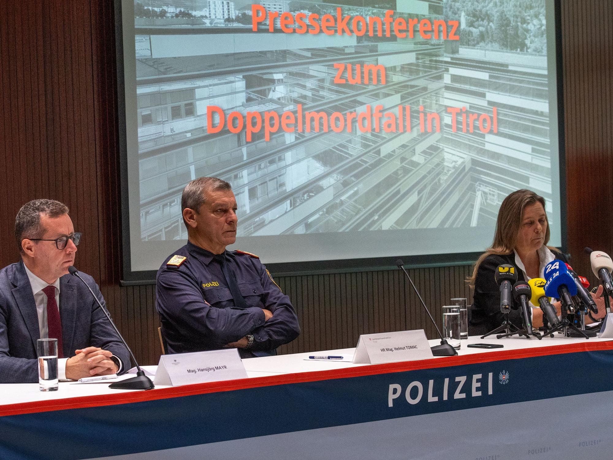 Zwei Männer und eine Frau sitzen bei einer Pressekonferenz an einem Tisch, auf dem das Wort Polizei steht.