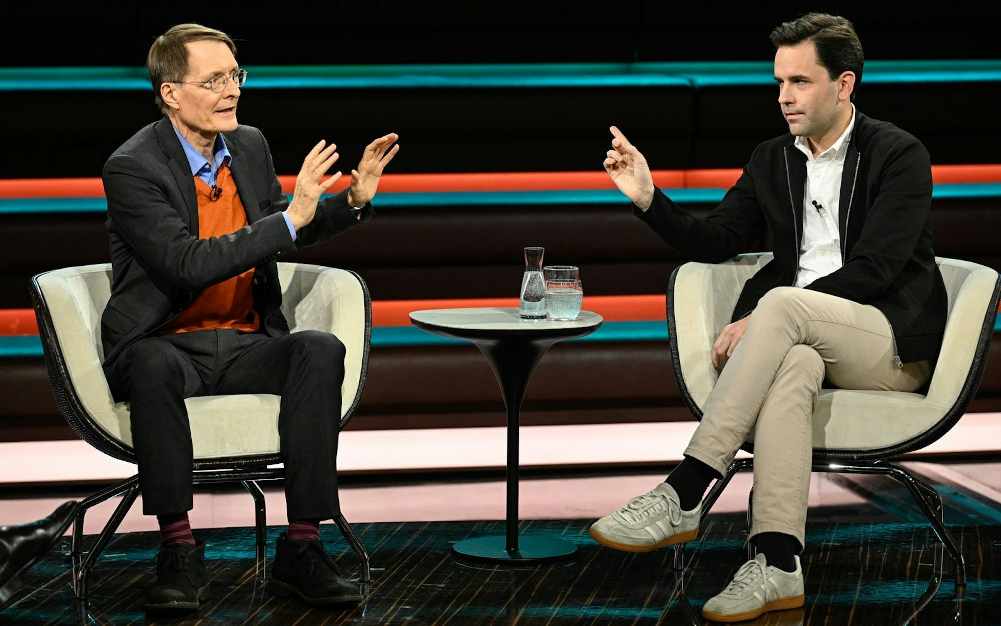 Zwei Männer sitzen sich in einem Fernsehstudio gegenüber.