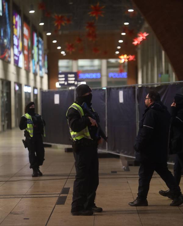 Zwei vermummte Personen stehen in einer Halle.