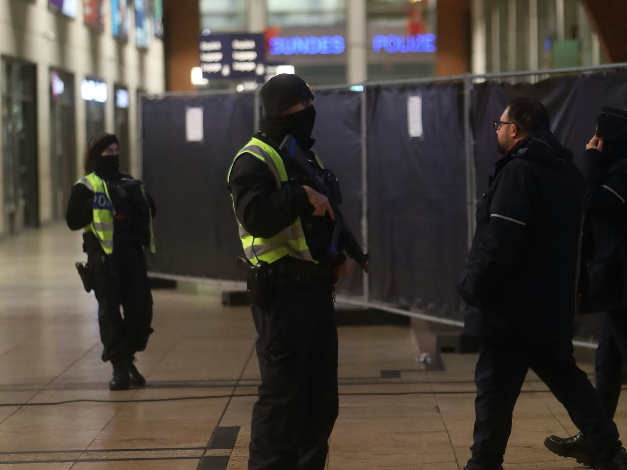 Zwei vermummte Personen stehen in einer Halle.