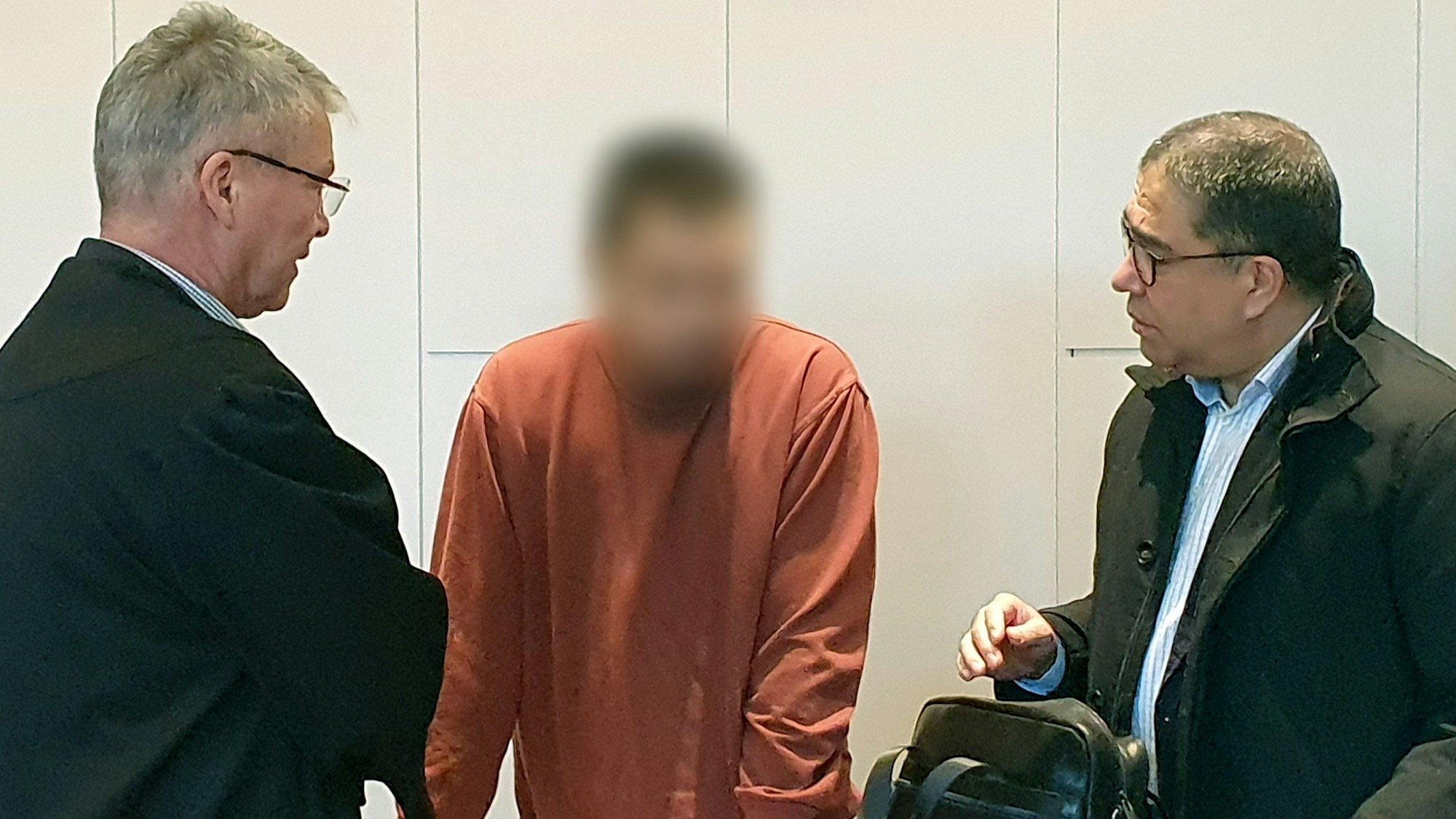 Der Angeklagte (Mitte) steht im Landgericht beim Prozess um den tödlichen Messerangriff in der Krefelder Filiale einer Modekette zwischen seinem Verteidiger Jörg Hintzen (links) und einem Dolmetscher.
