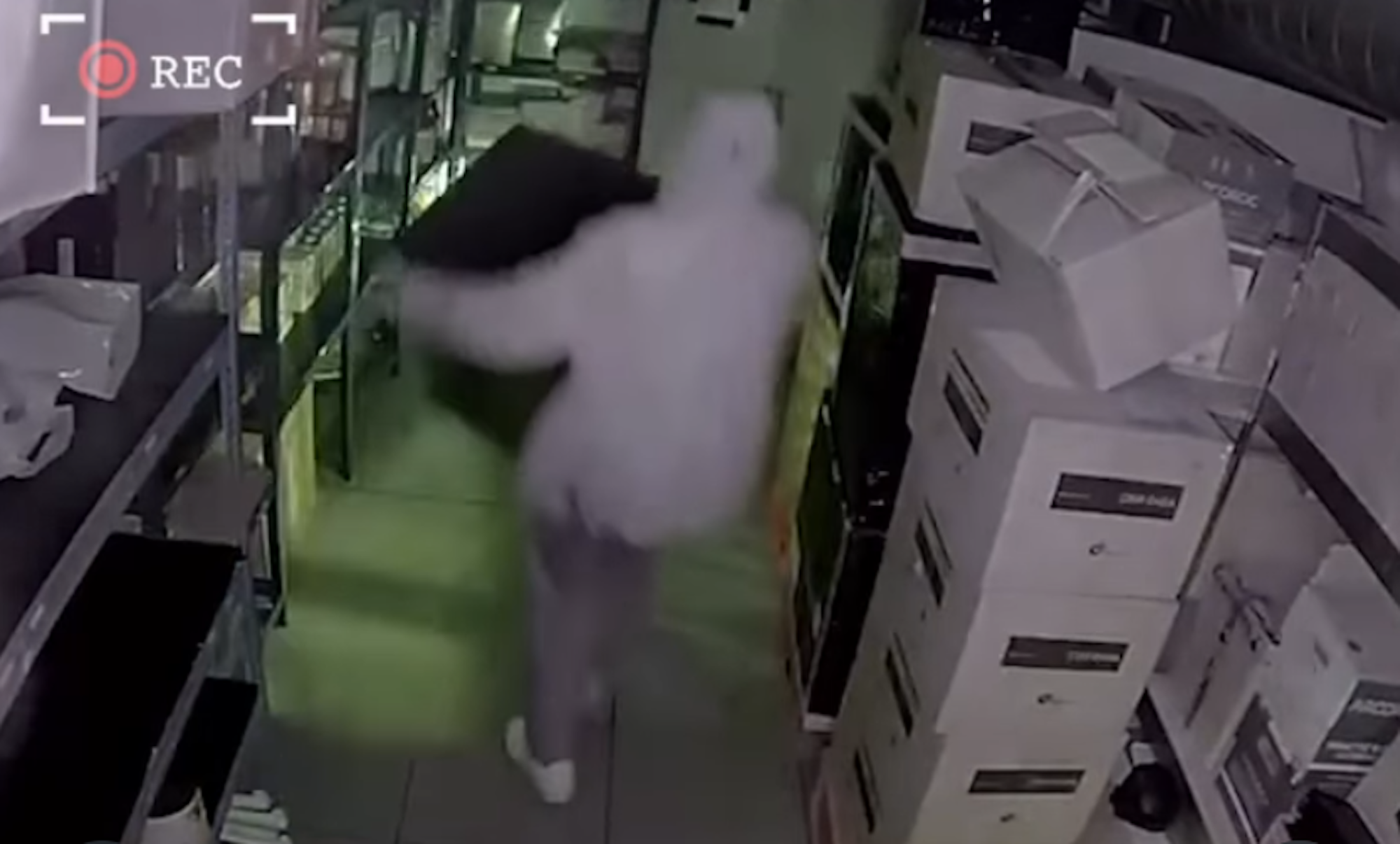 Einer der Täter versucht, den Safe aus dem Café zu tragen.