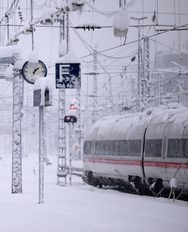 Zwei Züge stehen auf verschneiten Bahngleisen.