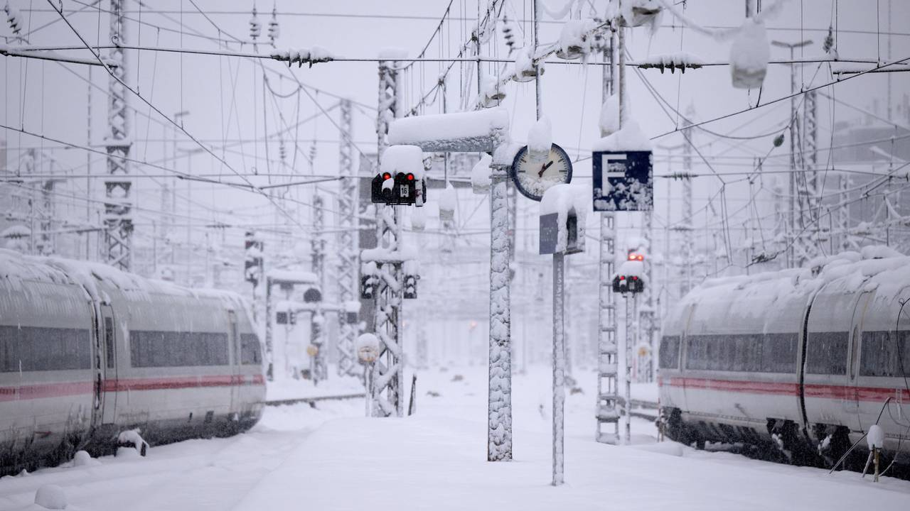 Zwei Züge stehen auf verschneiten Bahngleisen.