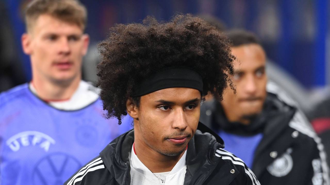 Karim Adeyemi mit schwarzem Stirnband, Lockenkopf und Trainingsjacke, Blick zur Seite gerichtet