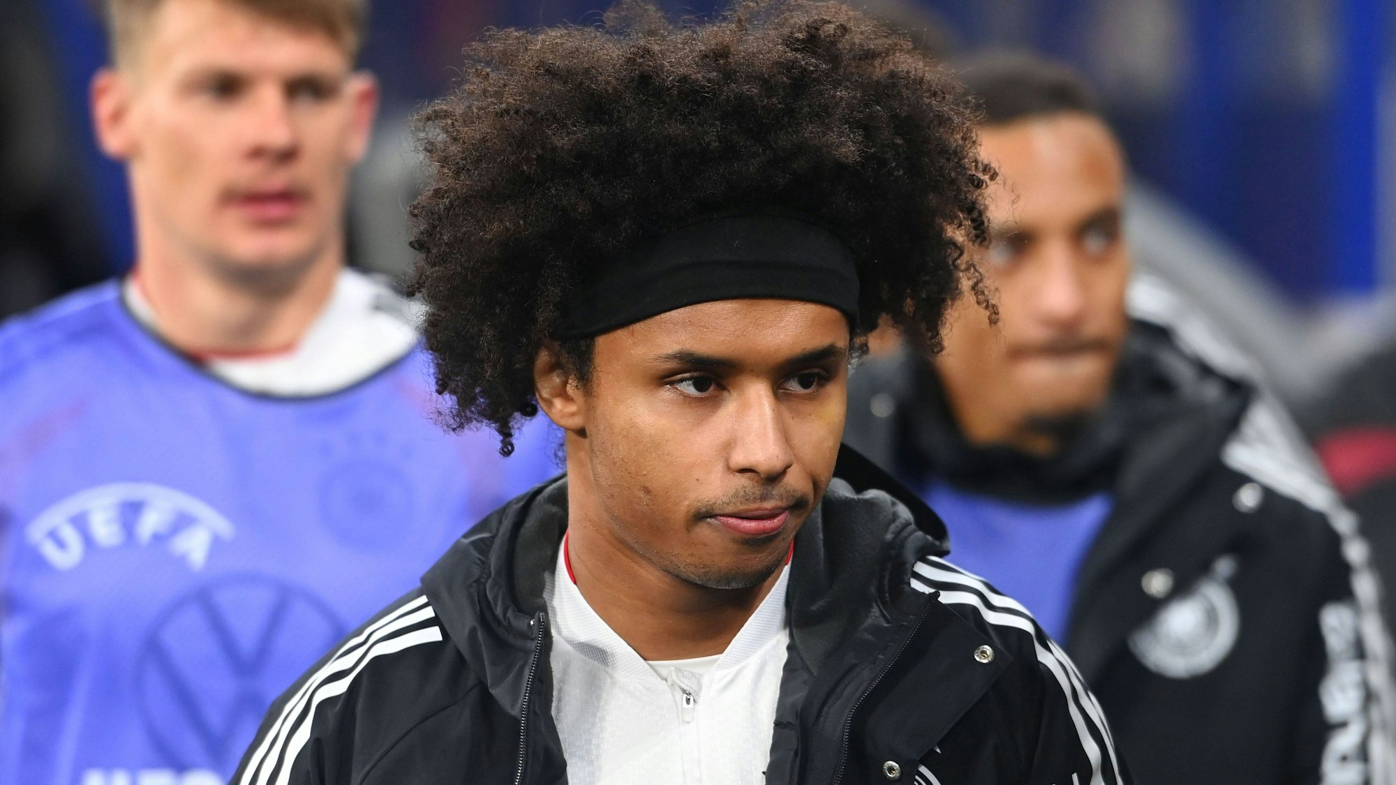 Karim Adeyemi mit schwarzem Stirnband, Lockenkopf und Trainingsjacke, Blick zur Seite gerichtet