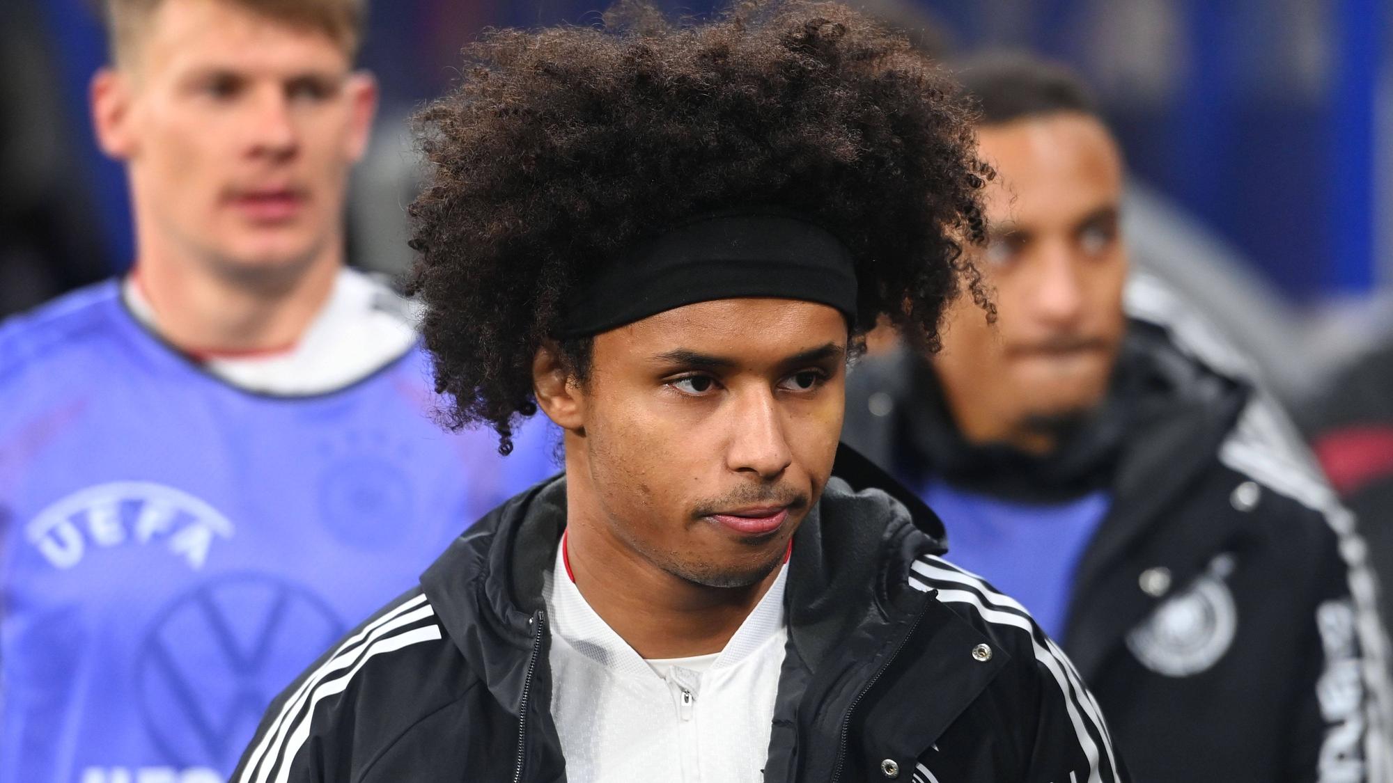 Karim Adeyemi mit schwarzem Stirnband, Lockenkopf und Trainingsjacke, Blick zur Seite gerichtet