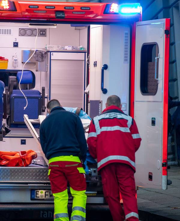 Zwei Männer schieben etwas in einen Rettungswagen.