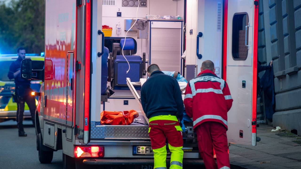 Zwei Männer schieben etwas in einen Rettungswagen.