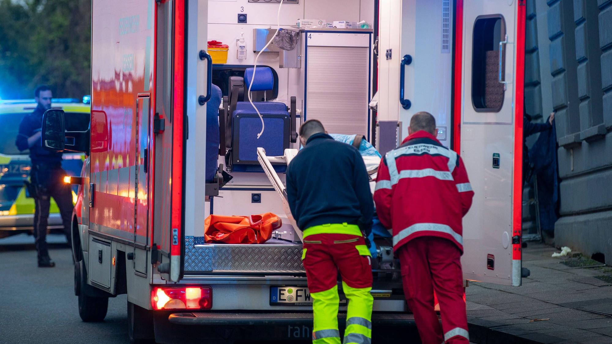 Zwei Männer schieben etwas in einen Rettungswagen.