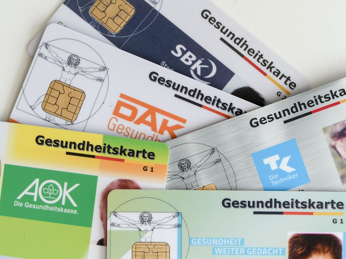Gesundheitskarten verschiedener Krankenkassen liegen auf einem Tisch.