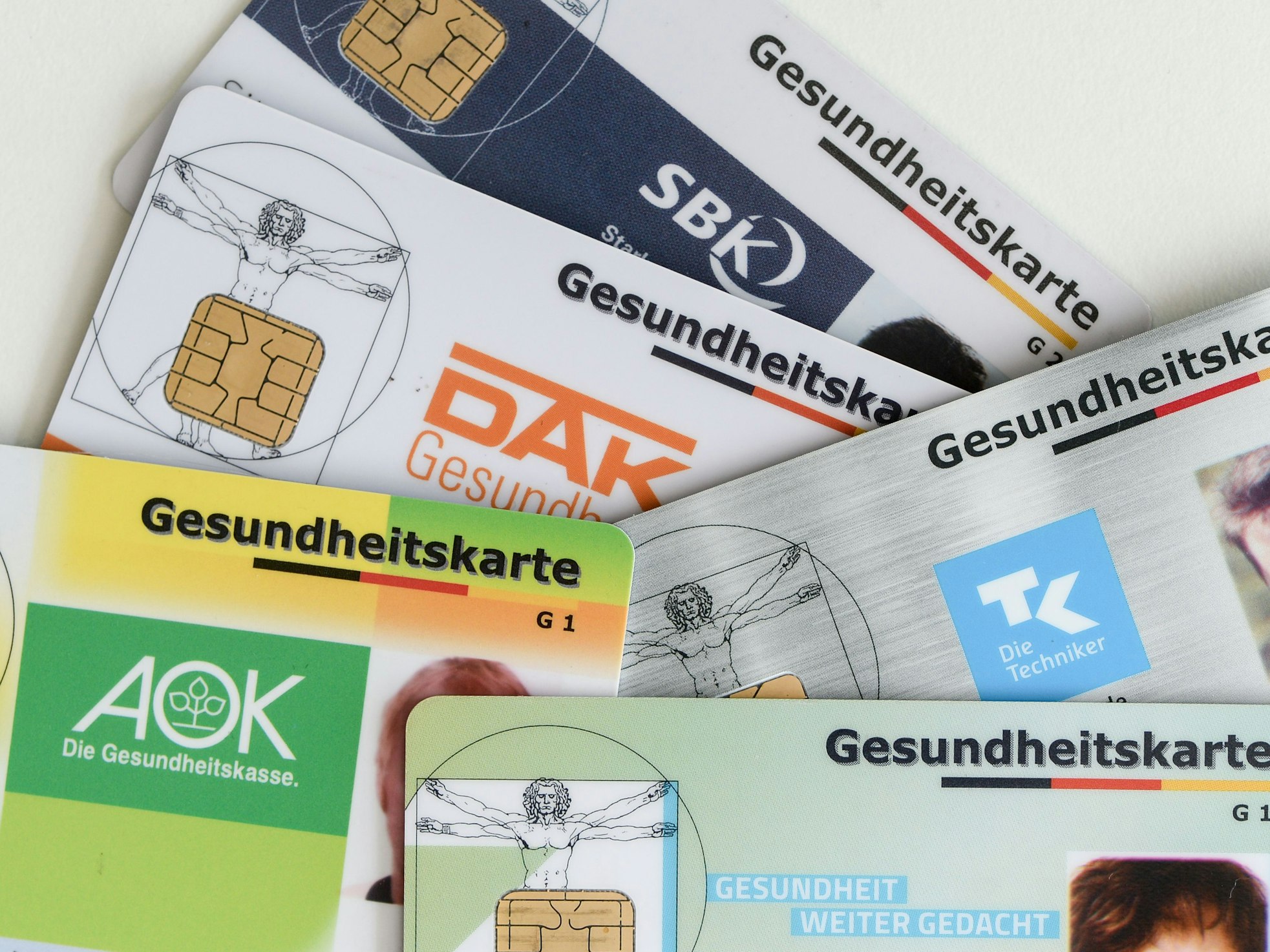 Gesundheitskarten verschiedener Krankenkassen liegen auf einem Tisch.