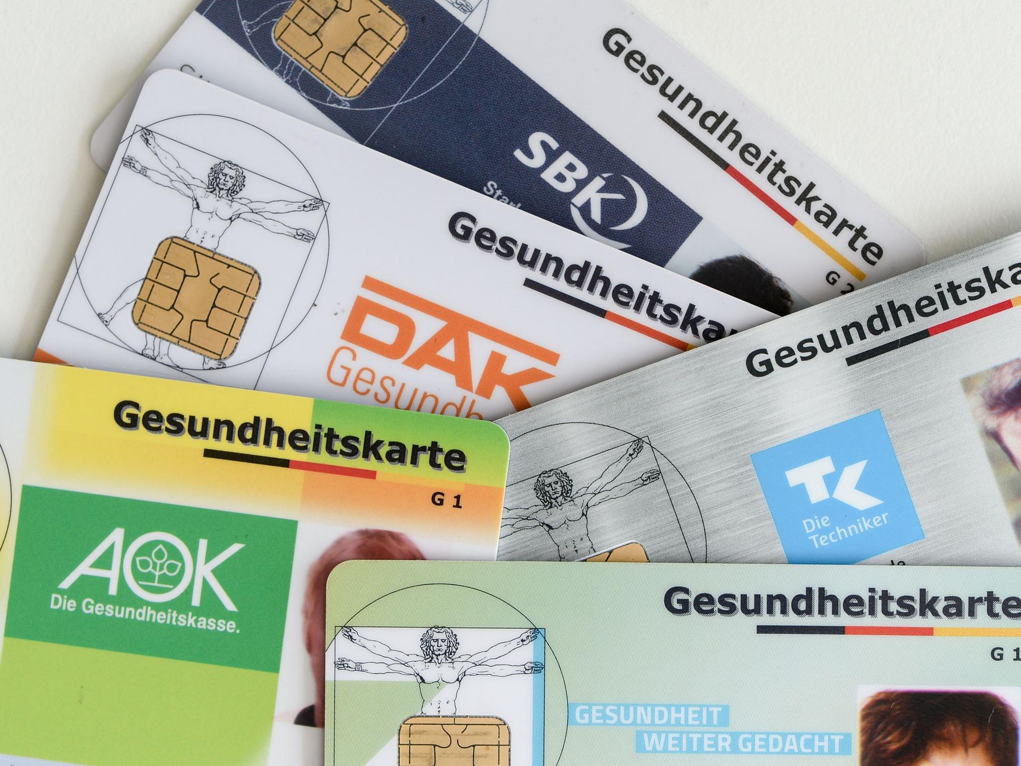 Gesundheitskarten verschiedener Krankenkassen liegen auf einem Tisch.