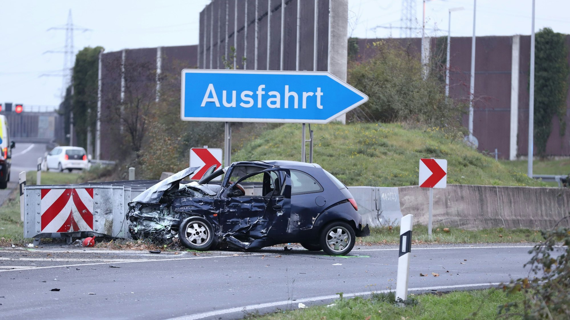 Ein schwer beschädigter Pkw steht in einer Autobahnausfahrt.