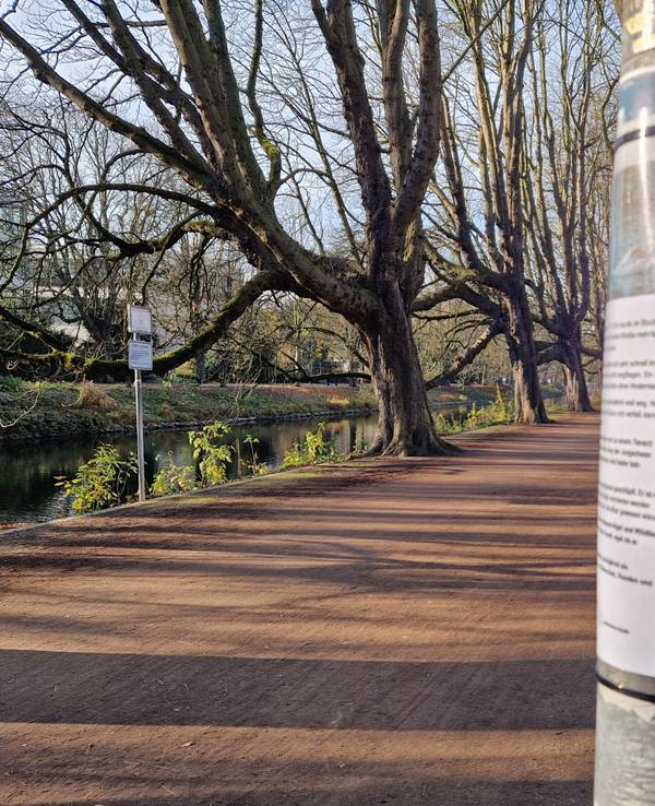 Am Clarenbachkanal in Köln-Lindenthal hängt ein laminiertes Schild an einem Metallpfal.