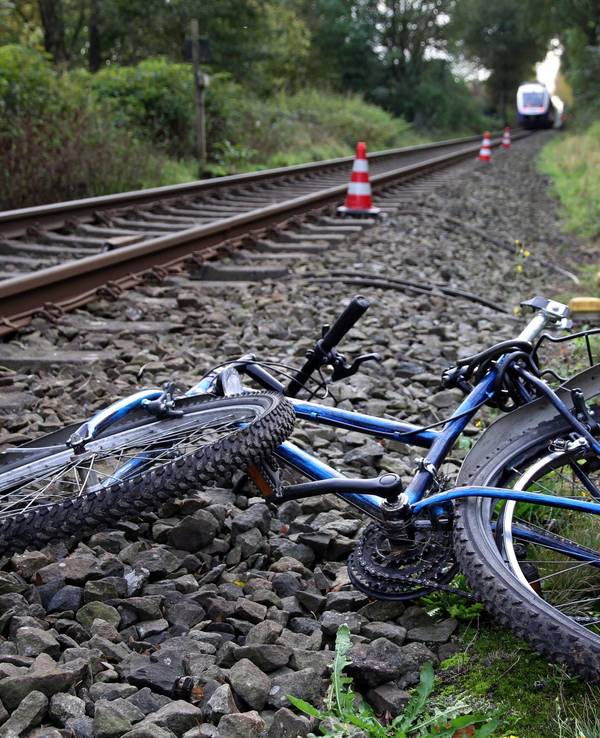 Ein stark beschädigtes Fahrrad liegt neben Bahngleisen.