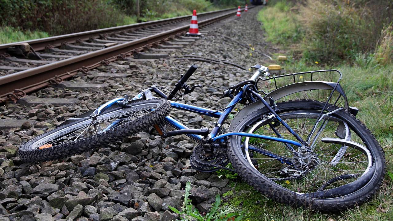 Ein stark beschädigtes Fahrrad liegt neben Bahngleisen.