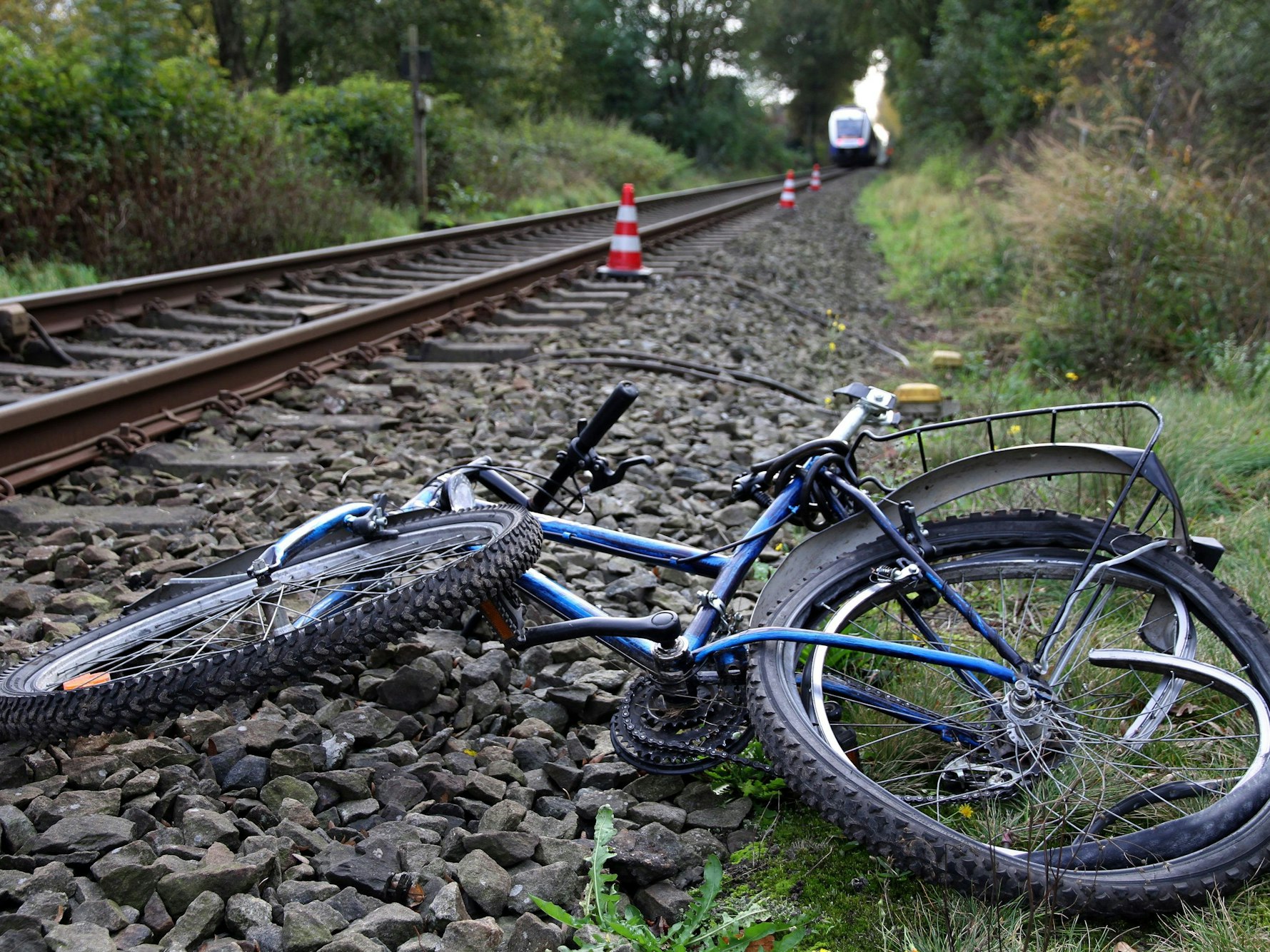 Ein stark beschädigtes Fahrrad liegt neben Bahngleisen.