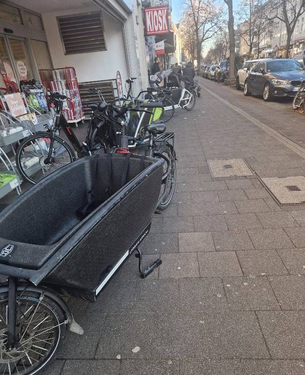 Lastenfahrräder stehen auf einem Bürgersteig.