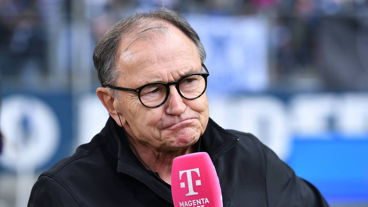 Ewald Lienen mit einem Mikrofon von MagentaSport.