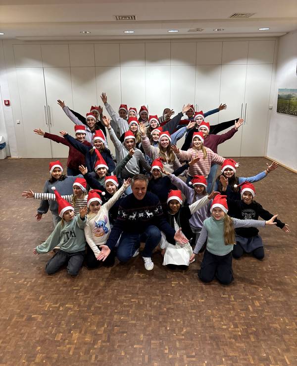 Die Lucky Kids mit Weihnachtsmützen auf dem Kopf bei der Chorprobe.