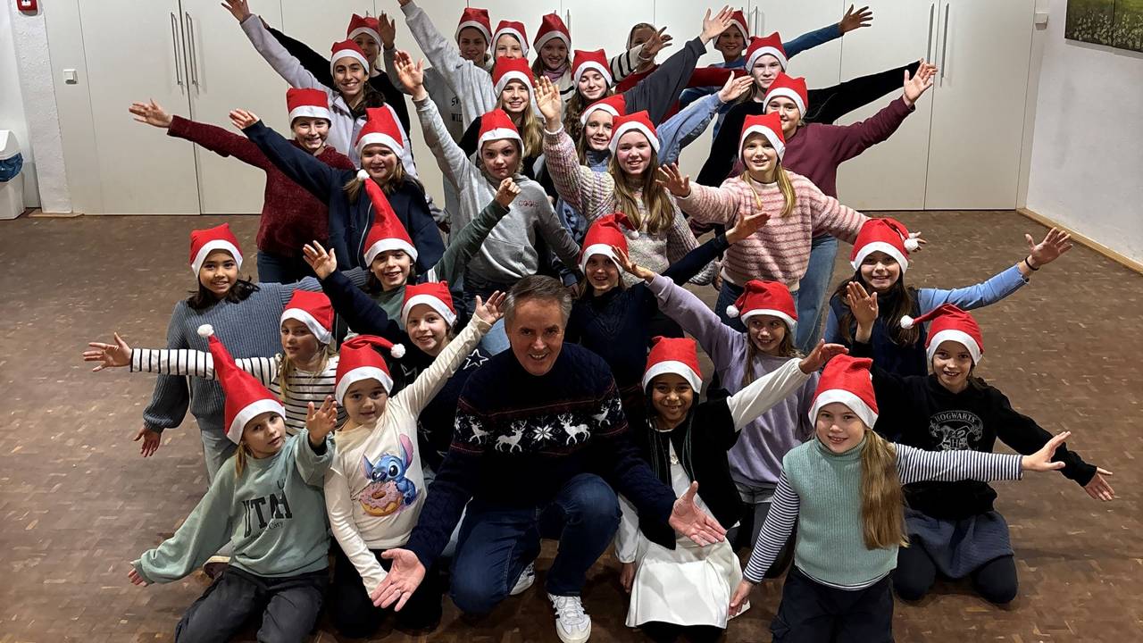Die Lucky Kids mit Weihnachtsmützen auf dem Kopf bei der Chorprobe.