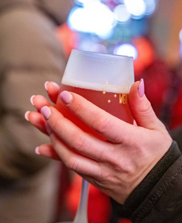 Eine junge Frau wärmt sich die Hände an einem Rosé-Glühwein.