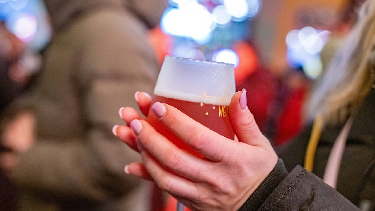 Eine junge Frau wärmt sich die Hände an einem Rosé-Glühwein.