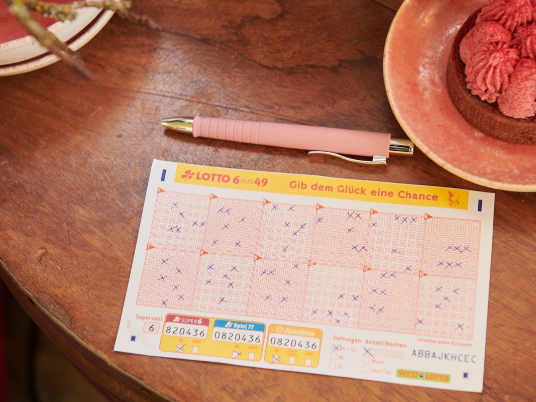 Ein Tippschein für Lotto 6aus49 liegt auf einem Holztisch.