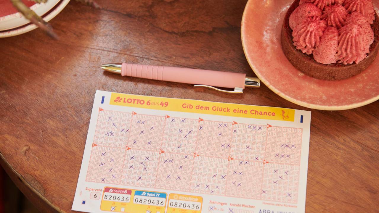 Ein Tippschein für Lotto 6aus49 liegt auf einem Holztisch.