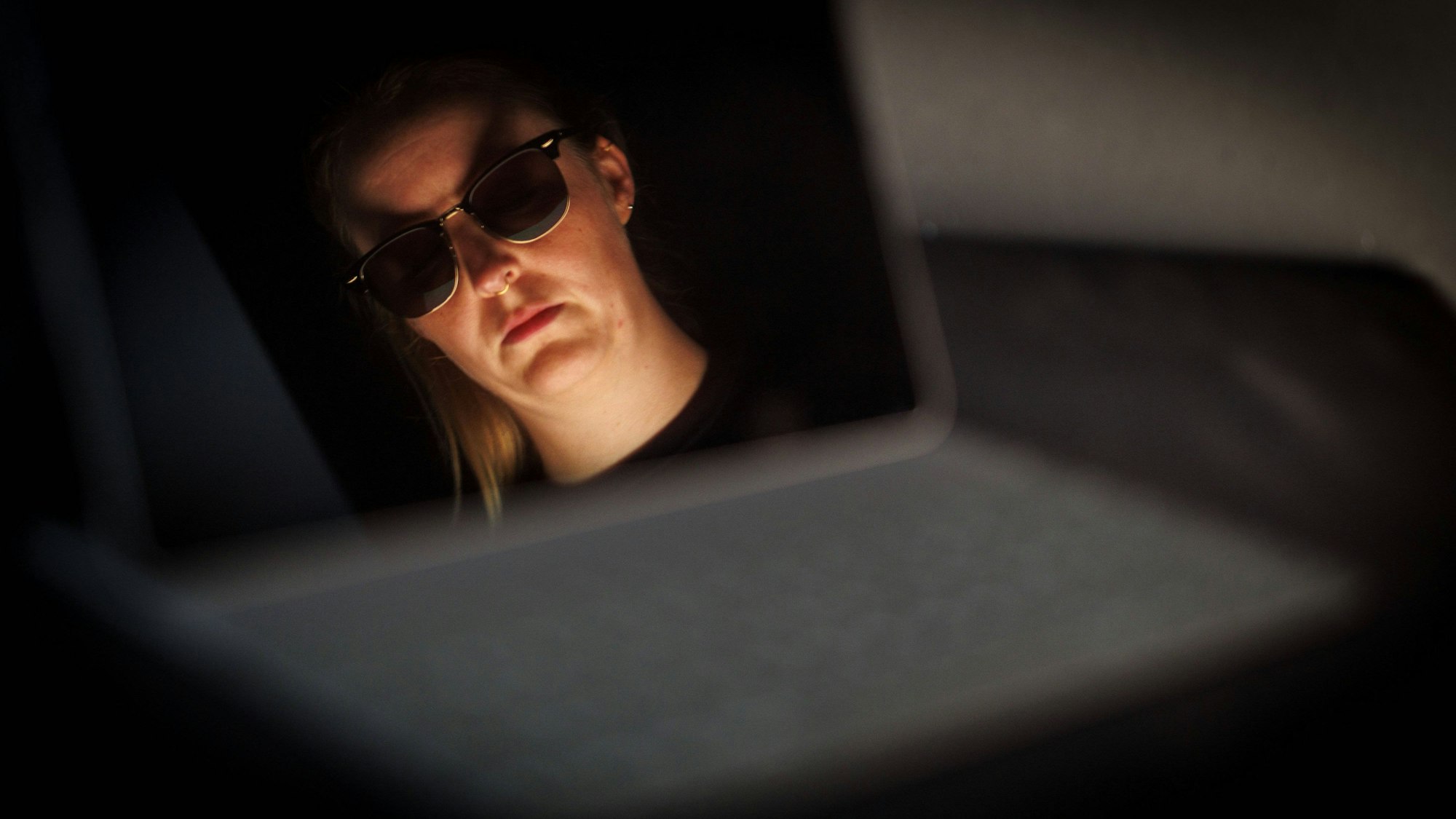 Porträt einer Frau mit Sonnenbrille und Nasenring, von unten beleuchtet