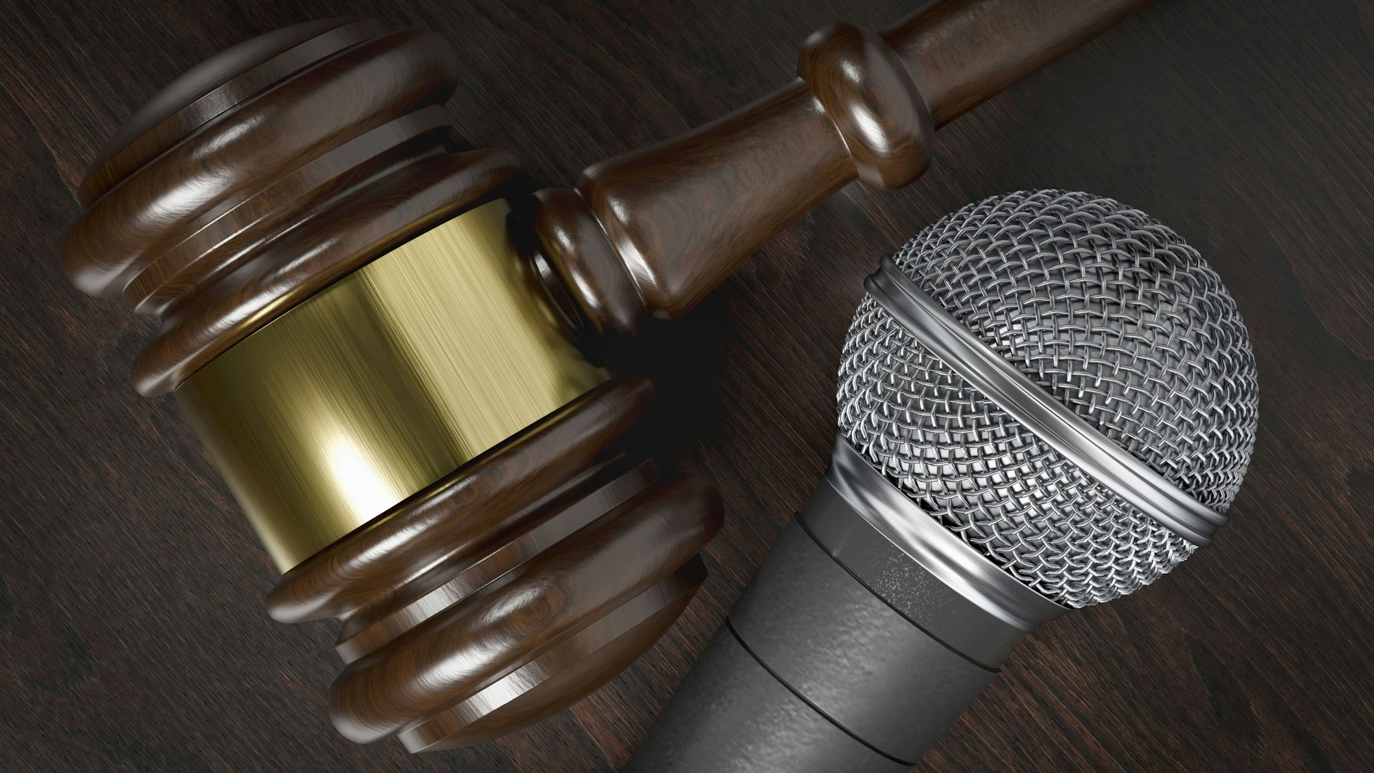 Nahaufnahme eines Richterhammers und eines Mikrofons auf einer dunklen Holzoberfläche