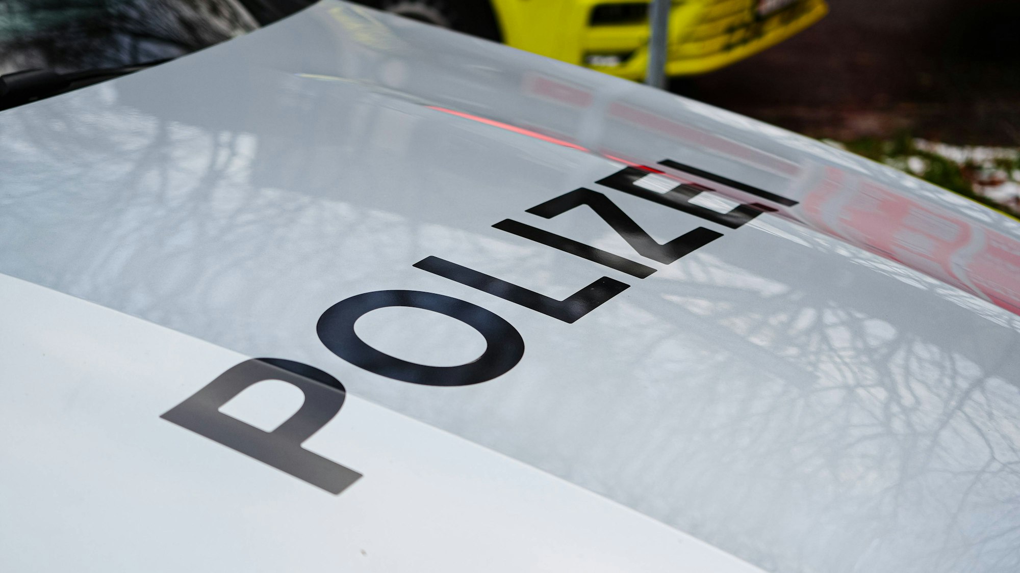 Symbolbild Polizei: Nahaufnahme des Schriftzugs POLIZEI auf der Motorhaube eines weißen Polizeifahrzeugs