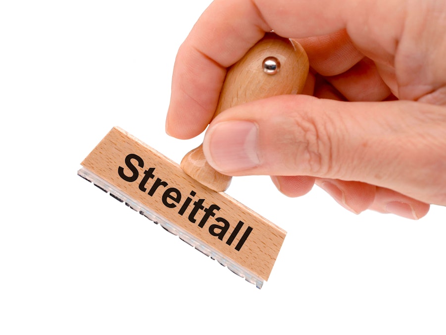 Hand hält Holzstempel mit der Aufschrift „Streitfall“