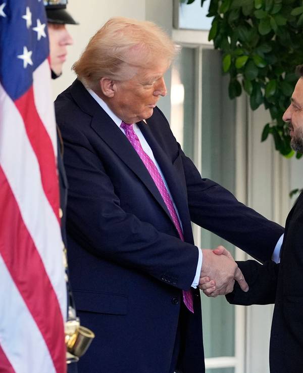 Zwei Männer geben sich die Hand, rechts die ukrainische, links die amerikanische Flagge.