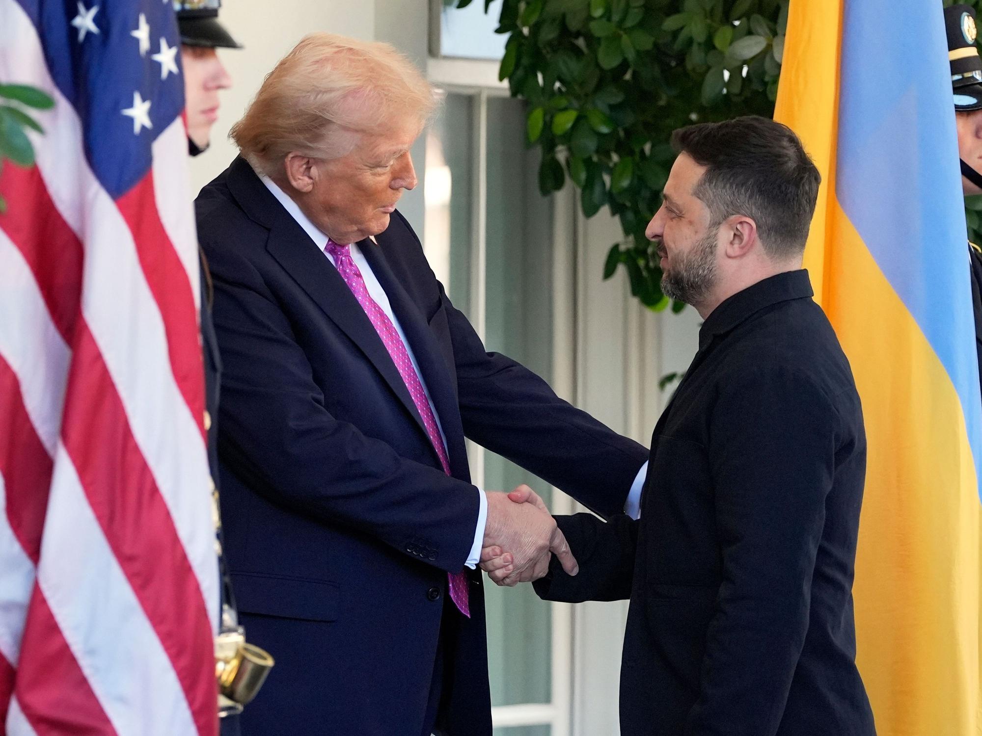 Zwei Männer geben sich die Hand, rechts die ukrainische, links die amerikanische Flagge.