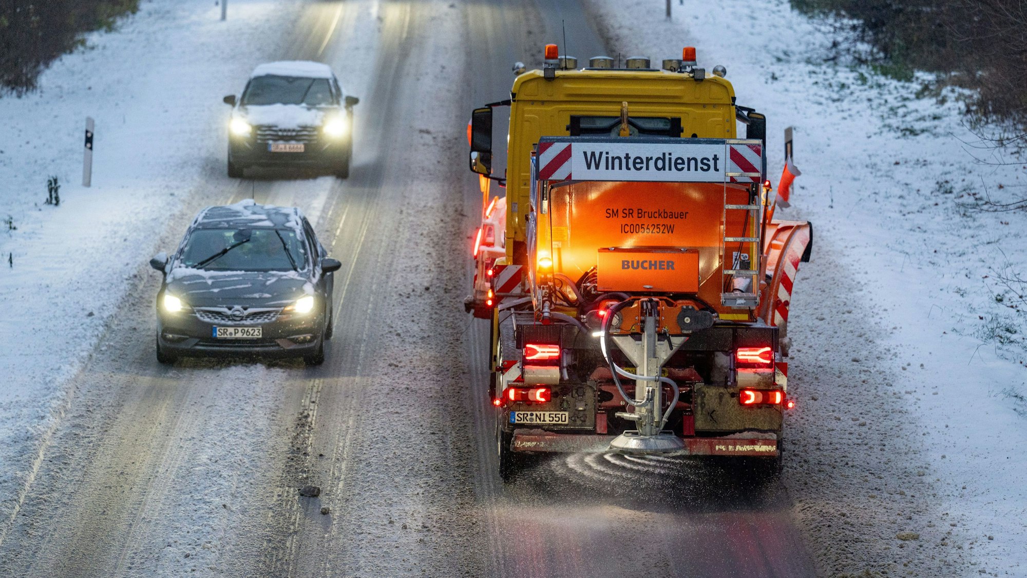 Ein Fahrzeug vom Winterdienst fährt auf der mit Schnee bedeckten Straße.