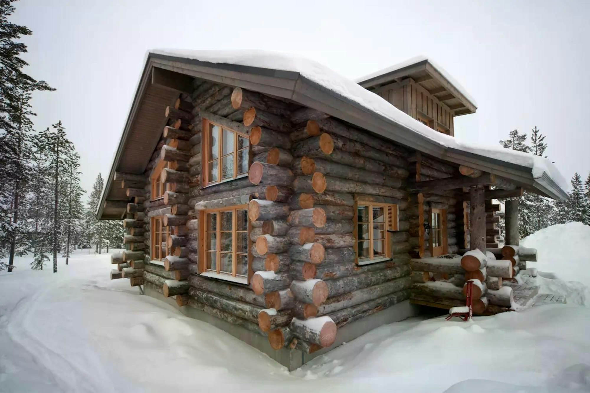 Das Bild zeigt eine gemütliche Hütte im verschneiten Winterwald in Finnisch-Lappland