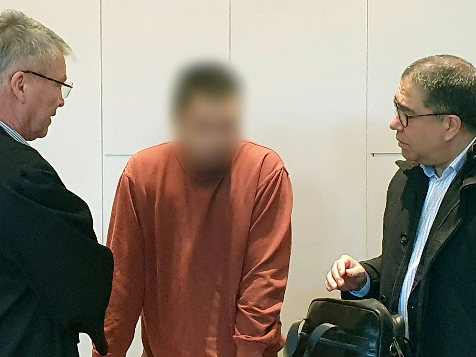 Der Angeklagte (M) steht im Landgericht beim Prozess um den tödlichen Messerangriff in der Krefelder Filiale einer Modekette zwischen seinem Verteidiger Jörg Hintzen (l) und einem Dolmetscher.