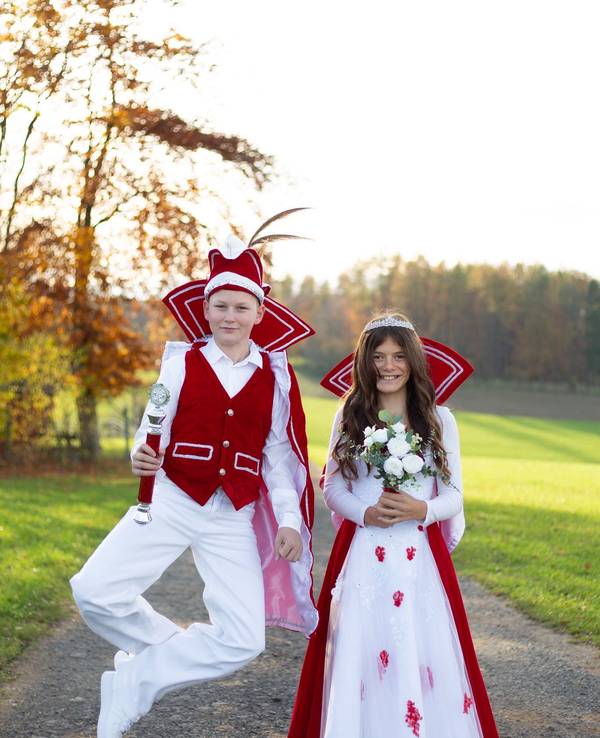 Emmi und Anton stehen im Ornat auf einem Weg, Anton hüpft in die Höhe.